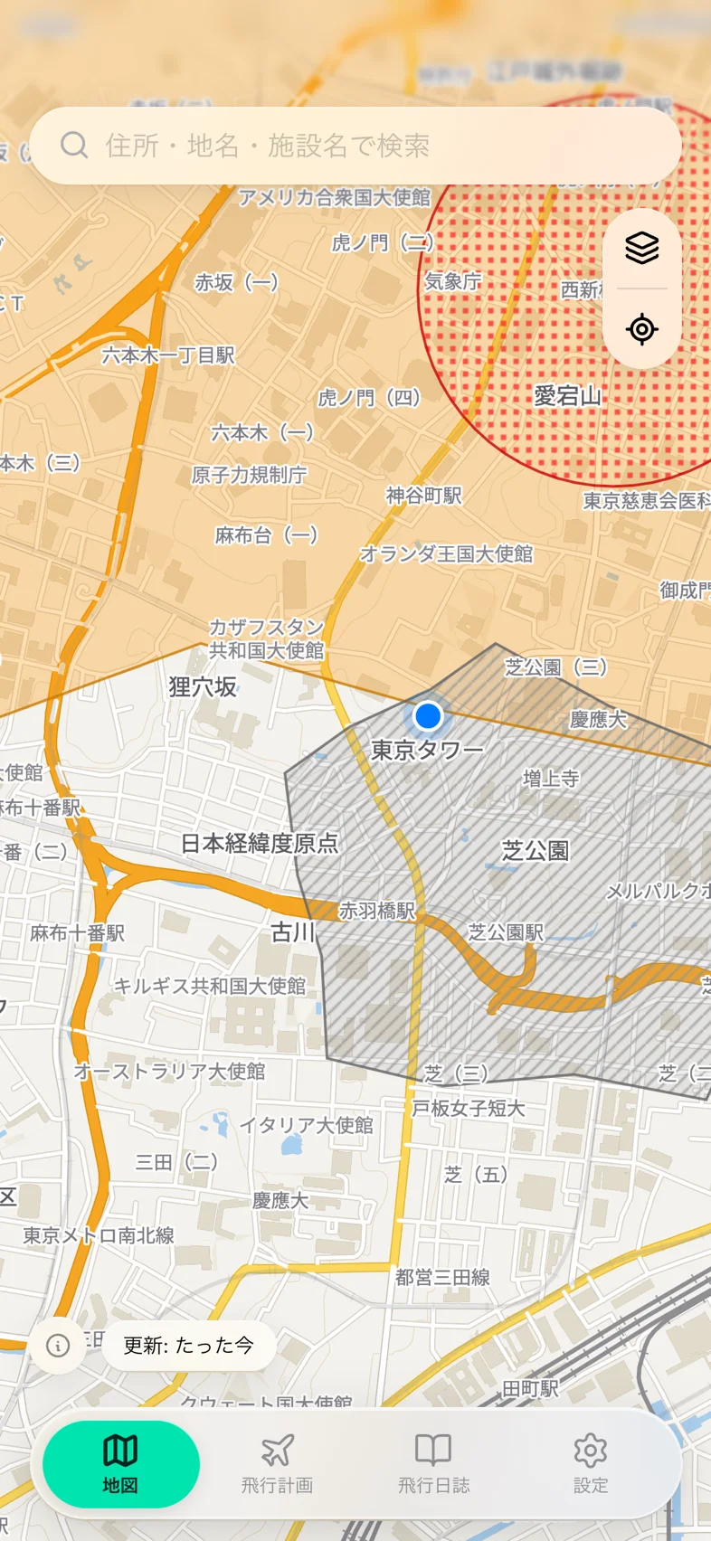 Drone24 の地図画面。飛行禁止区域が色と模様で重なり、上に検索欄、右上にレイヤーと現在地のボタンがある